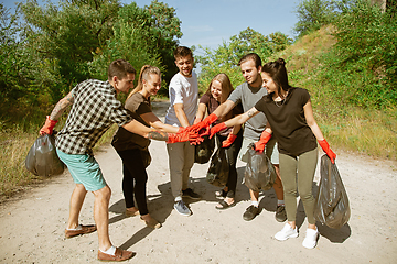 Image showing Group of volunteers tidying up rubbish on beach