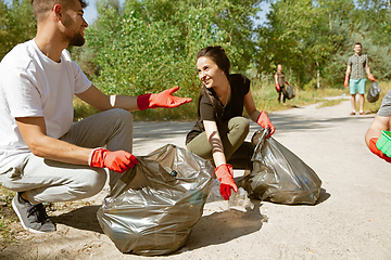 Image showing Group of volunteers tidying up rubbish on beach