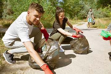 Image showing Group of volunteers tidying up rubbish on beach