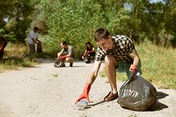 Image showing Group of volunteers tidying up rubbish on beach