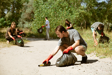 Image showing Group of volunteers tidying up rubbish on beach