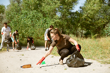 Image showing Group of volunteers tidying up rubbish on beach