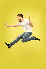 Image showing Full length portrait of happy jumping man on yellow background