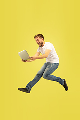 Image showing Full length portrait of happy jumping man on yellow background