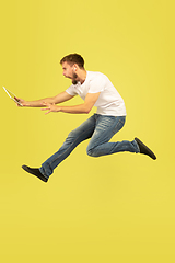 Image showing Full length portrait of happy jumping man on yellow background