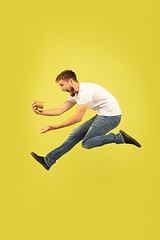 Image showing Full length portrait of happy jumping man on yellow background