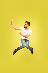 Image showing Full length portrait of happy jumping man on yellow background