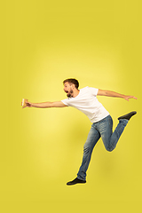 Image showing Full length portrait of happy jumping man on yellow background