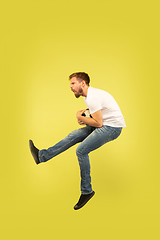 Image showing Full length portrait of happy jumping man on yellow background