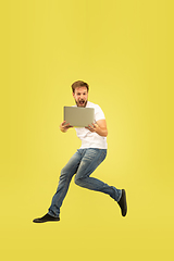 Image showing Full length portrait of happy jumping man on yellow background