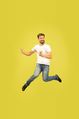 Image showing Full length portrait of happy jumping man on yellow background