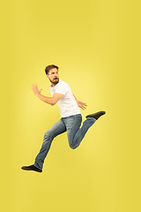 Image showing Full length portrait of happy jumping man on yellow background