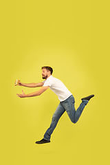 Image showing Full length portrait of happy jumping man on yellow background