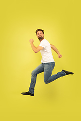 Image showing Full length portrait of happy jumping man on yellow background