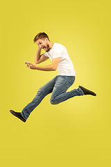 Image showing Full length portrait of happy jumping man on yellow background