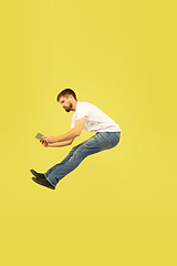 Image showing Full length portrait of happy jumping man on yellow background