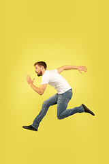 Image showing Full length portrait of happy jumping man on yellow background