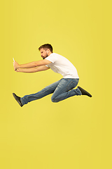 Image showing Full length portrait of happy jumping man on yellow background