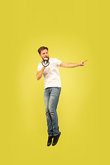 Image showing Full length portrait of happy jumping man on yellow background