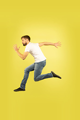 Image showing Full length portrait of happy jumping man on yellow background