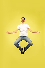 Image showing Full length portrait of happy jumping man on yellow background