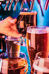 Image showing Hand of bartender pouring a large lager beer in tap