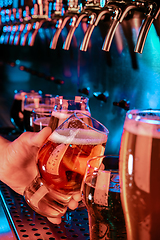 Image showing Hand of bartender pouring a large lager beer in tap