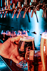 Image showing Hand of bartender pouring a large ale, porter, stout beer in tap