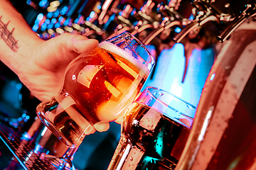 Image showing Hand of bartender pouring a large lager beer in tap