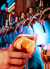 Image showing Hand of bartender pouring a large lager beer in tap