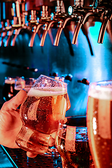 Image showing Hand of bartender pouring a large lager beer in tap