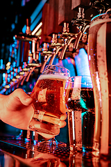 Image showing Hand of bartender pouring a large lager beer in tap