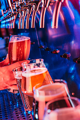 Image showing Hand of bartender pouring a large lager beer in tap