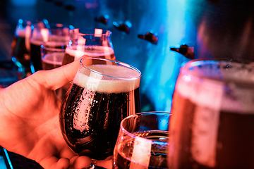 Image showing Hand of bartender pouring a large ale, porter, stout beer in tap