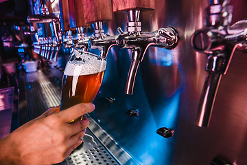 Image showing Hand of bartender pouring a large lager beer in tap