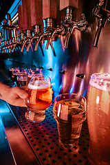 Image showing Hand of bartender pouring a large lager beer in tap