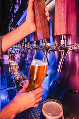 Image showing Hand of bartender pouring a large lager beer in tap