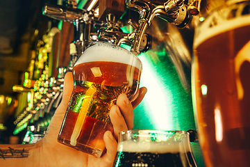 Image showing Hand of bartender pouring a large lager beer in tap