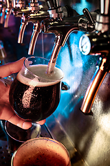 Image showing Hand of bartender pouring a large ale, porter, stout beer in tap