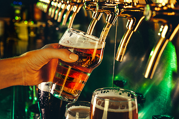 Image showing Hand of bartender pouring a large lager beer in tap