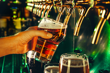 Image showing Hand of bartender pouring a large lager beer in tap