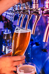 Image showing Hand of bartender pouring a large lager beer in tap