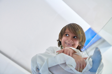 Image showing Portrait of arabian kid wearing traditional clothes sitting on the glass floor