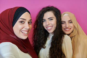 Image showing Muslim women taking selfie by mobile phone isolated on pink background