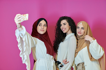 Image showing Muslim women taking selfie by mobile phone isolated on pink background