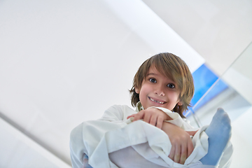 Image showing Portrait of arabian kid wearing traditional clothes sitting on the glass floor