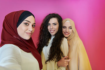 Image showing Muslim women taking selfie by mobile phone isolated on pink background