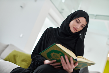 Image showing Portrait of young muslim woman reading Quran in modern home