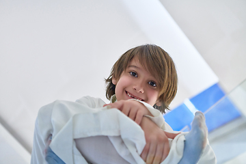 Image showing Portrait of arabian kid wearing traditional clothes sitting on the glass floor