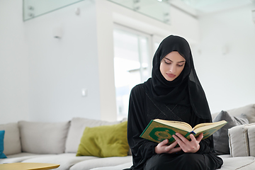 Image showing Portrait of young muslim woman reading Quran in modern home